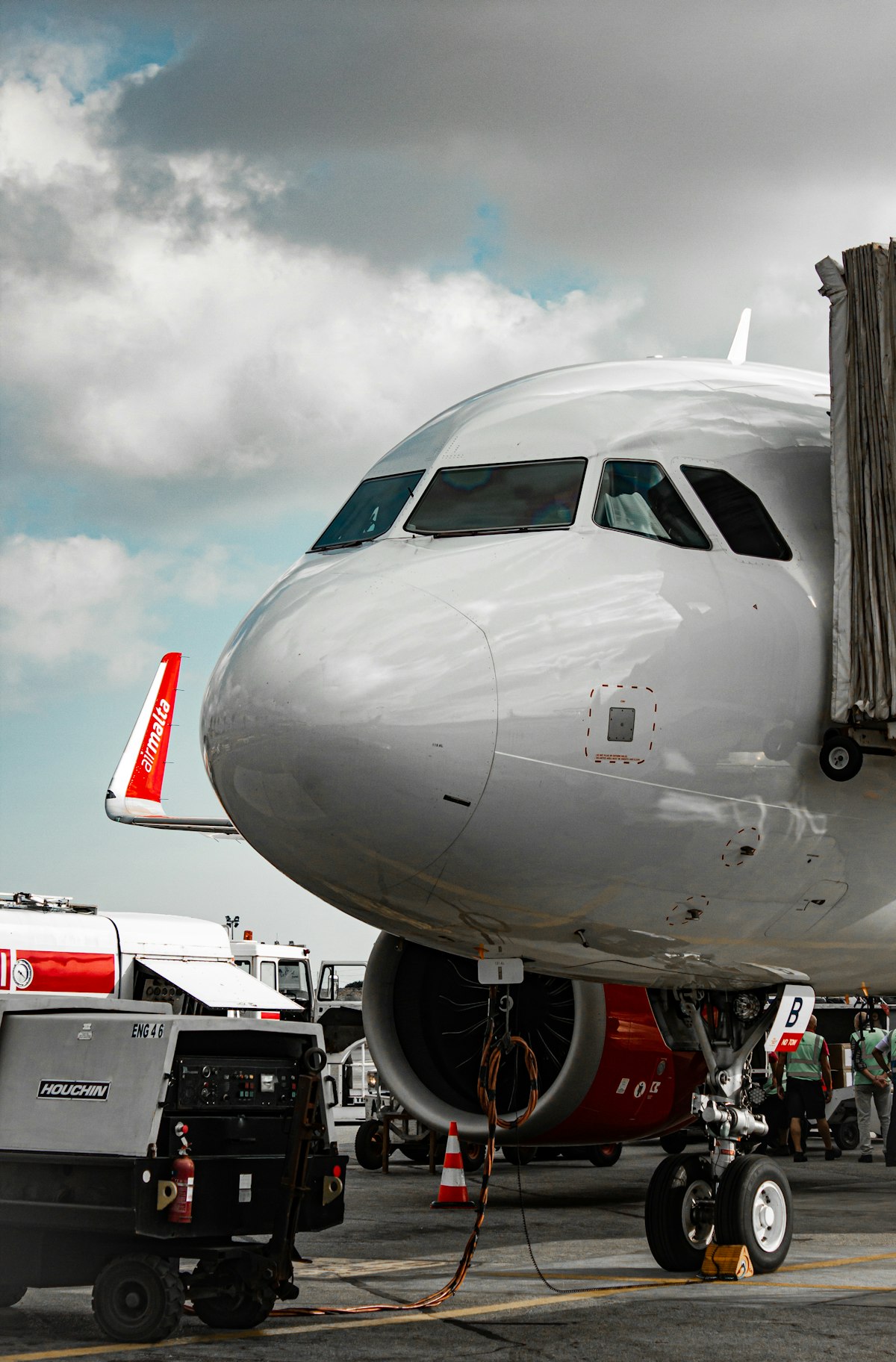 An airliner on the tarmac with a ground power unit connected